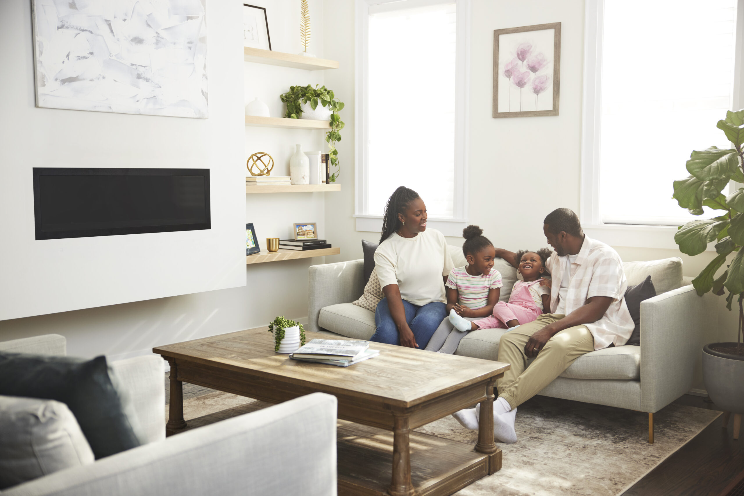 A mother, father and two daughters sit on a couch in a living room