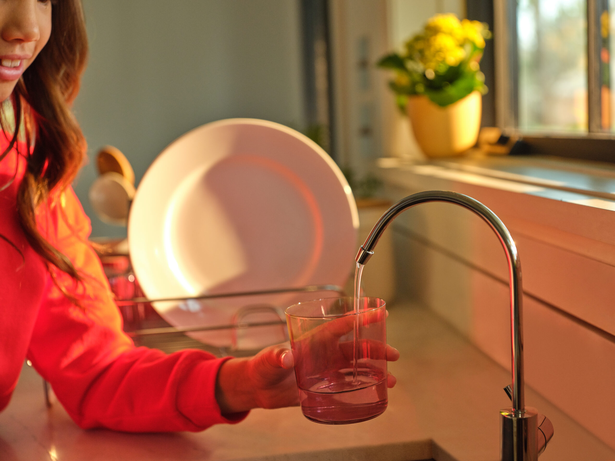 A girl fills a glass with water from a reverse osmosis system tap